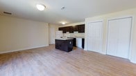 Located at 31 Harbor Dr in Claymont, Delaware, this single-floor residence offers a clean, functional layout designed for comfortable everyday living. The open-concept main area seamlessly connects the kitchen and living space, creating a sense of openness and ease of movement throughout.

The kitchen is a standout feature, outfitted with rich dark wood cabinetry that provides ample storage and a striking visual contrast against the light-toned walls. A central island offers additional workspace and serves as a natural gathering point within the open floor plan. The kitchen is equipped with a range, refrigerator, and dishwasher, and features a countertop sink with built-in counter space. Light hardwood-style flooring runs continuously throughout the space, contributing to a bright, cohesive aesthetic.

The living area benefits from its open connection to the kitchen, making it an inviting and versatile space. Multiple doors are visible throughout, indicating well-distributed storage solutions including a large closet. The neutral color palette of the walls and flooring ensures a timeless, adaptable backdrop for a variety of interior styles. Flush-mount ceiling lighting provides consistent illumination throughout the space. Overall, the residence presents a practical and well-appointed layout suited for a range of lifestyles.