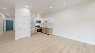 Located at 3000 T St in Sacramento, CA, this single-floor studio offers a thoughtfully designed open-concept layout that combines the kitchen and living area into one cohesive space. Light-toned luxury vinyl plank flooring runs throughout the main living area, complementing the crisp white walls and recessed lighting that keep the interior feeling bright and airy. A wall-mounted mini-split HVAC unit provides efficient climate control. The kitchen is outfitted with white upper cabinetry, warm wood-toned lower cabinets, stainless steel appliances including a range, microwave, and dishwasher, and a undermount sink — all finished with clean, modern detailing. Sliding glass doors in the living area open to an outdoor space, allowing natural light to filter in and providing a seamless connection to the exterior. The bathroom features gray tile flooring, a wall-mounted vanity with an LED-backlit mirror, and a walk-in shower adorned with marble-style tile surround. Brushed nickel grab bars throughout the bathroom add accessibility-conscious functionality. The overall aesthetic is clean, contemporary, and efficiently organized, making excellent use of the available footprint.