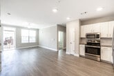 This single-floor residence offers a thoughtfully designed open-concept layout that seamlessly connects the living area and kitchen. The main living space features light hardwood-style flooring, neutral warm-toned walls, crown molding, recessed lighting, and a ceiling fan, creating a bright and welcoming atmosphere. Natural light flows in through multiple windows fitted with horizontal blinds.

The kitchen is well-equipped with white shaker-style cabinetry, granite countertops, a subway tile backsplash, and a full suite of stainless steel appliances including a refrigerator, range, dishwasher, and microwave. The open sightlines between the kitchen and living area make the space feel expansive and functional.

The bedrooms are finished with plush carpeting and feature corner or double windows that bring in generous natural light, each room equipped with a ceiling fan. The bathrooms are appointed with white vanity cabinetry, granite countertops, large mirrors with overhead lighting, and a soaking tub with tiled surround. Light wood-style flooring carries through the bathroom spaces, maintaining a cohesive aesthetic. Overall, the residence presents a clean, modern, and move-in-ready interior with consistent finishes throughout.