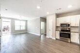 This single-floor residence offers a thoughtfully designed open-concept layout that seamlessly connects the living area and kitchen. The main living space features light hardwood-style flooring, neutral warm-toned walls, crown molding, recessed lighting, and a ceiling fan, creating a bright and welcoming atmosphere. Natural light flows in through multiple windows fitted with horizontal blinds.

The kitchen is well-equipped with white shaker-style cabinetry, granite countertops, a subway tile backsplash, and a full suite of stainless steel appliances including a refrigerator, range, dishwasher, and microwave. The open sightlines between the kitchen and living area make the space feel expansive and functional.

The bedrooms are finished with plush carpeting and feature corner or double windows that bring in generous natural light, each room equipped with a ceiling fan. The bathrooms are appointed with white vanity cabinetry, granite countertops, large mirrors with overhead lighting, and a soaking tub with tiled surround. Light wood-style flooring carries through the bathroom spaces, maintaining a cohesive aesthetic. Overall, the residence presents a clean, modern, and move-in-ready interior with consistent finishes throughout.