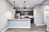 This thoughtfully designed 3-floor space offers a cohesive blend of modern finishes and functional layouts throughout. Light hardwood flooring flows consistently across all levels, complementing the neutral gray-toned walls and crisp white trim that define the interior aesthetic.

The kitchen serves as a central highlight, featuring a substantial island with a granite countertop, undermount sink, and seating overhang. Dark-toned shaker-style cabinetry pairs with a white subway tile backsplash and a full suite of stainless steel appliances, including a refrigerator, electric range, and built-in microwave. Industrial-style pendant lights add character overhead.

The bathrooms are well-appointed with dark shaker vanities topped with granite countertops, large mirrors, and tile-surround walk-in showers. Light hardwood flooring continues into these spaces, maintaining a unified design language throughout.

The open living areas are generously proportioned and benefit from natural light through windows offering exterior views. Wall-mounted mini-split units provide climate control in the living spaces. A staircase with a wood handrail connects all three floors, with a convenient stacked washer and dryer unit tucked neatly into a dedicated laundry closet on one of the upper levels.