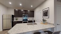 Located at 3986 Parkmead Dr in Grove City, Ohio, this single-floor home offers a thoughtfully designed open-concept layout that seamlessly connects the living, dining, and kitchen areas. The kitchen is a standout feature, equipped with dark espresso cabinetry, granite countertops, stainless steel appliances including a range, over-the-range microwave, and refrigerator, and a large center island with an undermount sink and bar seating for three — ideal for casual dining and entertaining. Recessed lighting illuminates the space, while wood-look flooring flows throughout the main living areas, adding warmth and cohesion. The living room is bright and inviting, featuring a large window that brings in generous natural light. The bedrooms are carpeted for comfort, each with large windows fitted with blinds for privacy and light control. The bathroom is well-appointed with a dark-cabinetry vanity topped with granite, a full mirror, and a shower/tub combination. Neutral wall tones throughout the home create a clean, modern aesthetic that complements the contemporary finishes. The overall design balances practicality with style, making this Grove City home a functional and attractive living space.