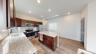 Located in Colorado Springs, Colorado, this single-story home offers a well-designed, open layout that maximizes functionality and comfort. The kitchen serves as the heart of the home, showcasing rich dark wood cabinetry, granite countertops, a subway tile backsplash, and a full suite of stainless steel appliances, including a range, microwave, and refrigerator. A central island with matching granite provides additional prep and storage space. Wood-look luxury vinyl flooring flows throughout the main living and kitchen areas, lending warmth and continuity to the open-concept design.

The living area is bright and inviting, with neutral walls, a ceiling fan, and a wall-mounted mini-split unit for climate control. Natural light filters in through multiple windows fitted with horizontal blinds. The entryway features a distinctive arched door with sidelights, creating an attractive and welcoming first impression.

Bedrooms are carpeted for comfort and include ceiling fans, wall-mounted mini-split units, and windows that bring in ample daylight. The bathroom is clean and functional, featuring a granite-topped vanity with dark cabinetry, wood-look flooring, and a tub-shower combination. Overall, the home presents a cohesive, modern aesthetic with practical finishes throughout.