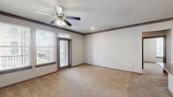 Located in Humble, TX, this single-story, 3-bedroom, 2-bathroom home offers a well-designed layout with a practical mix of finishes and functional spaces. The kitchen serves as a central highlight, featuring dark espresso cabinetry, granite countertops, a peninsula with a stainless steel sink, and a full suite of stainless steel appliances including a refrigerator, range, and microwave. Wood-style plank flooring runs through the kitchen and entry areas, lending warmth and easy maintenance to high-traffic zones. The living area is generously proportioned, finished with plush carpet, crown molding, a ceiling fan, and access to an outdoor balcony through a glass door flanked by windows that allow ample natural light. Each bedroom offers carpeted flooring, ceiling fans, and windows with exterior views. The spacious primary bedroom is complemented by an en-suite bathroom featuring a dual-sink granite vanity with dark cabinetry, wood-style flooring, and a tub-shower combination with white tile surround. A second full bathroom mirrors this clean aesthetic with a tub-shower unit and neutral finishes. Storage is well-addressed throughout, with three closets including a walk-in closet equipped with wire shelving systems. Two hallways connect the living spaces efficiently, completing this thoughtfully organized home.
