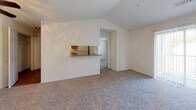 This single-floor residence offers a thoughtfully arranged layout that balances open living areas with well-defined private spaces. The living room serves as the heart of the home, showcasing vaulted ceilings and a ceiling fan with a light fixture overhead. Plush neutral carpeting flows throughout the living and bedroom areas, while a pass-through window connects the living space directly to the kitchen, enhancing the open feel. The galley-style kitchen is equipped with warm wood cabinetry, ample upper and lower storage, a double-basin sink, and white appliances including a range and refrigerator, all set on durable wood-look flooring.

Two carpeted bedrooms each feature windows with blinds that invite natural light and outdoor views. One bedroom includes a sliding-door closet with a hanging rod for convenient storage. Both full bathrooms are finished with wood-look flooring, a tub-shower combination with white tile surround, a toilet, and a vanity with a wood cabinet base and mirror. A dedicated in-unit laundry closet houses a side-by-side washer and dryer. The overall aesthetic is clean and neutral, offering a bright and functional living environment.