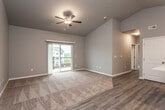 This single-floor residence offers a thoughtfully designed open-concept layout that balances comfort and functionality. The spacious living area features soaring vaulted ceilings and a ceiling fan, creating an airy atmosphere. Soft carpeting anchors the living space, which transitions seamlessly to durable wood-look vinyl flooring throughout the kitchen and entryway areas. A sliding glass door floods the room with natural light and opens to a private balcony with neighborhood views.

The kitchen is a standout feature, showcasing rich, dark espresso cabinetry paired with crisp white countertops and a full suite of stainless steel appliances, including a range, microwave, dishwasher, and refrigerator. A kitchen island provides additional prep and serving space, while pendant lighting adds a finishing touch.

The bedrooms are generously sized, each featuring plush carpet, ceiling fans, and windows that bring in natural light and exterior views. The bathroom is finished with large-format tile flooring, dark cabinetry, a wide vanity with an oversized mirror, and a full tub-shower combination. A dedicated in-unit laundry area adds everyday convenience. Neutral gray walls and consistent finishes throughout give the space a clean, cohesive, and move-in ready aesthetic.