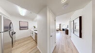 Located at 1770 N Green Valley Parkway in Las Vegas, Nevada, this well-appointed two-bedroom, two-bathroom residence offers a thoughtfully designed single-floor layout. Light wood flooring flows throughout, lending warmth and continuity to every room.

The open living room is bright and welcoming, featuring large windows dressed with layered blinds and floor-to-ceiling curtains that frame views of the surrounding greenery. A fireplace anchors one wall, adding a cozy focal point to the space. The kitchen is outfitted with white shaker cabinetry, light countertops, and stainless steel appliances including a gas range and full-size refrigerator.

The primary bedroom is generously sized and features a sliding glass door that opens to a private outdoor balcony with scenic views — a standout feature of the space. The second bedroom is bright and comfortable, with a large window and ample room for furnishings. Each bedroom benefits from dedicated closet space.

Both bathrooms are finished in a clean, neutral palette with tiled tub-shower combinations, light wood-style flooring, and framed wall art adding a curated touch. Two hallways provide smooth circulation throughout the layout. The overall ambiance is light, airy, and modern — ideal for comfortable everyday living in the heart of the Las Vegas Valley.