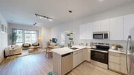 Located at 415 Stump Rd in Montgomeryville, PA, this well-appointed 2-bedroom, 2-bathroom residence offers a thoughtfully designed single-floor layout with modern finishes throughout. The open-concept kitchen and living area serves as the heart of the home, featuring a central island with bar seating, sleek white upper cabinetry paired with warm wood-toned lower cabinets, stainless steel appliances, and light wood-style flooring that flows seamlessly into the living room. Track lighting and a statement pendant light illuminate the space, while large windows flood the living area with natural light and offer outdoor views. The living room provides a comfortable and airy atmosphere, accentuated by high ceilings and oversized windows with sheer drapery. Both bedrooms are carpeted and serene, with the primary bedroom offering a generous footprint, a closet, and windows that bring in natural light. The two bathrooms are finished with clean, contemporary details — one features a large sliding-glass walk-in shower with matte black hardware, while the other is styled with wood-look flooring and a vanity. Two dedicated closets provide ample storage. The overall aesthetic is bright, clean, and modern, creating a cohesive and inviting living environment.