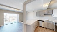 This single-floor unit offers a well-organized layout comprising two bedrooms, a living room, a kitchen, and a connecting hallway. Light wood-style flooring runs consistently throughout the space, lending a cohesive and clean aesthetic.

The kitchen is efficiently designed with gray shaker-style cabinetry, white quartz countertops, and a full suite of stainless steel appliances including a refrigerator, dishwasher, and range. A peninsula with additional cabinetry provides extra storage and partially separates the kitchen from the adjacent living area. Textured ceilings are present throughout the unit.

The living room is a bright, open area highlighted by a sliding glass door that opens to a balcony with expansive water views, allowing substantial natural light to fill the space.

Both bedrooms feature light wood-style flooring, louvered bi-fold closet doors for storage, and windows that bring in natural light. The primary bedroom is a comfortable size, while the secondary bedroom offers a similarly clean and neutral finish. A hallway connects the bedrooms to the main living areas, contributing to an efficient flow throughout the unit.