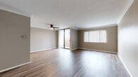 This 1-bedroom, 1-bathroom residence offers a thoughtfully organized single-floor layout that balances comfort and functionality. The spacious living room is a standout feature, showcasing warm hardwood-style flooring, neutral taupe walls, a ceiling fan, and large sliding glass doors that flood the space with natural light and provide direct access to the balcony. The balcony itself features a decorative lattice-patterned concrete railing and offers pleasant views of the surrounding neighborhood greenery.

The kitchen is well-equipped with white cabinetry, light countertops, a tile backsplash, and white appliances including a range, built-in microwave, and dishwasher. Light tile flooring completes the clean, bright aesthetic of this space.

The generously sized bedroom features plush wall-to-wall carpeting, warm neutral tones, and a large window dressed with vertical blinds that allow for adjustable natural light. A dedicated closet provides convenient storage.

The bathroom is finished with white cabinetry, a single-sink vanity with a dark-accented faucet, a large mirror, tile flooring, and a glass-enclosed shower, creating a clean and modern feel. Hallways connect the rooms efficiently, and the overall design presents a cohesive, neutral palette throughout.