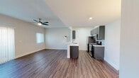 Located at 3317 Castle Heights Ave in Los Angeles, CA, this single-floor unit offers a clean, modern aesthetic throughout its well-designed layout. The open-concept living and kitchen area is anchored by rich, dark hardwood-style flooring that flows seamlessly across the main living spaces. A ceiling fan overhead adds both function and style to the bright, airy living room, which receives natural light through vertical-blind-covered windows.

The kitchen is a standout feature, equipped with stainless steel appliances including a gas range, microwave, and refrigerator. Sleek dark gray cabinetry with modern hardware lines the walls, complemented by a light tile backsplash and white countertops. A peninsula with a built-in sink serves as both a functional workspace and a natural divider between the kitchen and living area.

The bedroom offers plush carpeting, neutral tones, and a window with vertical blinds that allow for natural light and outdoor views. The bathroom is clean and functional, featuring a full shower-tub combo with chrome fixtures and a vanity with a light stone countertop. Throughout the unit, white walls and recessed lighting create a bright, cohesive atmosphere well-suited to modern urban living.
