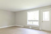 Located at 407 Sidney St, Unit 7 in Quinte West, Ontario, this 2-bedroom, 1-bathroom unit offers a practical and well-appointed single-floor layout. Light wood laminate flooring flows consistently throughout the living spaces, creating a clean and cohesive look. The living room is a comfortable, open area featuring a large window and balcony door that frame lush greenery views, allowing ample natural light to fill the room. A baseboard heating system runs along the perimeter, and a textured ceiling adds a subtle architectural detail.

The galley-style kitchen is efficiently designed with white shaker-style cabinetry, marble-look countertops, a stainless steel sink, and stainless steel appliances including a refrigerator and stove. Grey tile flooring and abundant upper and lower cabinet storage make this a highly functional space.

The primary bedroom is a well-sized room with a large window overlooking outdoor greenery, baseboard heating, and a sliding closet. The second bedroom is a comfortable, neutral-toned room with its own window and natural light.

The full bathroom is finished in a clean, white palette featuring a tiled tub-and-shower surround, a white vanity with storage, and neutral tile flooring. A connecting hallway ties all rooms together efficiently, completing this move-in ready unit.