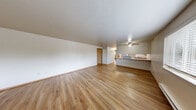 Located at 1521 N 26th St in Mount Vernon, Washington, this three-bedroom, one-bathroom residence offers a practical and well-organized single-floor layout. Warm wood-style flooring runs throughout the entire unit, creating a cohesive and clean aesthetic from room to room.

The combined kitchen and living area serves as the heart of the home. The kitchen is equipped with light maple cabinetry, white appliances including an electric range and refrigerator, ample counter space, and a convenient pass-through breakfast bar with a ceiling fan overhead — ideal for casual dining or meal prep. The adjacent living room is open and airy, featuring a wide window that brings in natural light and a baseboard heating system.

All three bedrooms are comfortably sized, with the primary bedroom offering a sliding-door closet and direct access to the hallway. The additional bedrooms each include windows that invite natural light and views of the surrounding greenery, along with their own closet storage.

The bathroom features a single vanity with light wood cabinetry and a large mirror. A notable highlight is the in-unit laundry area, which includes a full-size washer and dryer — a practical convenience. A central hallway connects all rooms efficiently, completing this functional and move-in-ready layout.