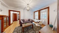 Located at 418 Claremount in the prestigious Westmount neighbourhood of Quebec, this 2-bedroom, 1-bathroom residence elegantly combines classic architectural character with contemporary finishes. Throughout the unit, warm hardwood flooring and rich mahogany-stained door and window trims provide a cohesive, timeless aesthetic, while crown moulding adds a refined finishing touch to each room.

The living area is generously proportioned and anchored by a decorative brick fireplace framed by a handsome wooden mantle with leaded glass cabinetry. An ornate globe chandelier illuminates the space, which flows seamlessly into a dedicated dining area bathed in natural light from large, multi-pane windows. A second sitting area near the entry offers added flexibility.

The kitchen has been fully renovated and features crisp white cabinetry with brushed nickel hardware, quartz countertops, a subway tile backsplash in muted grey tones, stainless steel appliances, and a striking polished marble-effect tile floor — a sophisticated contrast to the home's traditional character.

Both bedrooms are bright and well-sized, each with hardwood floors, large windows, and a calm, neutral palette. The primary bedroom includes a seating area and wall art nook, adding a comfortable, functional dimension to the room. The layout is efficient and thoughtfully arranged, making excellent use of the single-floor footprint.