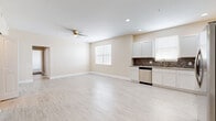 Located at 277 Champions Way in Davenport, Florida, this single-story home presents a clean, modern interior designed for comfortable everyday living. The open-concept layout seamlessly connects the living area and kitchen, creating a spacious, airy environment filled with natural light from well-placed windows. Light wood-look flooring spans the main living spaces, complemented by warm beige walls and crisp white trim throughout.

The kitchen is well-appointed with white shaker-style cabinetry extending to the upper walls, granite-look countertops, and a mosaic tile backsplash in earthy tones. A full suite of stainless steel appliances includes a refrigerator with ice maker, electric range, over-the-range microwave, and dishwasher. Recessed lighting illuminates the space, while a ceiling fan in the living area adds to year-round comfort.

The bedrooms offer a quiet retreat, with some featuring plush carpet flooring and large windows that invite natural light. One bedroom includes access to a walk-in closet with built-in shelving. The bathroom is finished with white subway tile surrounding a full soaking tub. The overall ambiance throughout is light, neutral, and move-in ready.