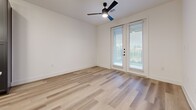 Located at 2908 East Howard Lane in Manor, TX, this thoughtfully designed one-bedroom, one-bathroom residence offers a clean, modern aesthetic across a well-utilized single floor. Light wood-tone flooring runs throughout the entire space, creating a cohesive and airy feel.

The kitchen serves as the centerpiece of the home, showcasing slate-gray shaker-style cabinetry extending to the ceiling for generous storage, bright white countertops, stainless steel appliances including a French door refrigerator, electric range, and over-the-range microwave. A white kitchen island with a matte black faucet provides additional prep space and is accented by globe pendant lights overhead.

The open living area benefits from natural light and features French doors that lead to an outdoor area, complemented by a ceiling fan. The bedroom is a comfortable size, filled with natural light through a large window, with direct access to the full bathroom. The bathroom features matching gray cabinetry, white countertops, black hardware accents, and a tiled shower/tub combination.

Storage is a standout feature, with four closets throughout the unit — including a spacious walk-in closet with built-in shelving and double hanging rods. The entrance provides a welcoming transition into this well-appointed home.