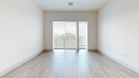 Located at 40 William St in Wellesley Hills, MA, this well-appointed 2-bedroom, 3-bathroom residence offers a thoughtfully designed single-floor layout with a clean, modern aesthetic. Light wood-tone flooring flows seamlessly throughout the space, complementing the bright white walls and creating a warm, cohesive atmosphere.

The open-concept kitchen and living area serves as the heart of the home. The kitchen is outfitted with rich dark walnut-finish cabinetry that extends floor to ceiling, stainless steel appliances including a refrigerator, range, and microwave, a light tile backsplash, white quartz countertops, and a central island with a sink — ideal for both cooking and casual dining. Recessed lighting illuminates the space efficiently.

The living room benefits from large sliding glass doors that invite abundant natural light and offer views of the surrounding greenery. The primary bedroom is a comfortable retreat with direct access to an en-suite bathroom featuring dark wood vanity cabinetry, white countertops, and a soaking tub with elegant marble-style tile surround. A dedicated walk-in closet with wire shelving provides ample storage.

The second bedroom is bright and airy with a large window framing outdoor tree views. Two additional closets round out the storage options, making this a highly functional and stylish residence in a desirable Wellesley Hills location.