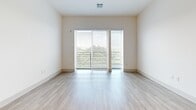 Located at 40 William St in Wellesley Hills, MA, this well-appointed 2-bedroom, 3-bathroom residence offers a thoughtfully designed single-floor layout with a clean, modern aesthetic. Light wood-tone flooring flows seamlessly throughout the space, complementing the bright white walls and creating a warm, cohesive atmosphere.

The open-concept kitchen and living area serves as the heart of the home. The kitchen is outfitted with rich dark walnut-finish cabinetry that extends floor to ceiling, stainless steel appliances including a refrigerator, range, and microwave, a light tile backsplash, white quartz countertops, and a central island with a sink — ideal for both cooking and casual dining. Recessed lighting illuminates the space efficiently.

The living room benefits from large sliding glass doors that invite abundant natural light and offer views of the surrounding greenery. The primary bedroom is a comfortable retreat with direct access to an en-suite bathroom featuring dark wood vanity cabinetry, white countertops, and a soaking tub with elegant marble-style tile surround. A dedicated walk-in closet with wire shelving provides ample storage.

The second bedroom is bright and airy with a large window framing outdoor tree views. Two additional closets round out the storage options, making this a highly functional and stylish residence in a desirable Wellesley Hills location.