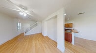 This two-story home offers a clean, functional layout with thoughtful design details throughout. The main level features light wood-style flooring that runs through the open living and dining areas, creating a warm and cohesive feel. The living room is anchored by a ceiling fan and sliding glass doors that flood the space with natural light and provide outdoor views. Adjacent to the living area, an arched passageway leads to the kitchen, which is well-appointed with warm-toned wood cabinetry, granite-style countertops, a double-basin sink, and a full suite of stainless steel appliances including a refrigerator, electric range, and microwave. A dedicated dining area nearby features a pendant light fixture and multiple windows overlooking the surrounding greenery. A convenient half bathroom is also located on the main floor. A carpeted staircase leads to the upper level, where the bedrooms are finished with plush carpet and feature natural light from corner and single windows. The bedrooms include closet space, with at least one walk-in closet offering full-width wire shelving. A full bathroom on the upper level includes a single vanity, toilet, soaking tub, and a bright window. The home's clean white walls and neutral finishes provide a versatile, move-in ready canvas throughout.
