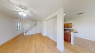 This two-story home offers a clean, functional layout with thoughtful design details throughout. The main level features light wood-style flooring that runs through the open living and dining areas, creating a warm and cohesive feel. The living room is anchored by a ceiling fan and sliding glass doors that flood the space with natural light and provide outdoor views. Adjacent to the living area, an arched passageway leads to the kitchen, which is well-appointed with warm-toned wood cabinetry, granite-style countertops, a double-basin sink, and a full suite of stainless steel appliances including a refrigerator, electric range, and microwave. A dedicated dining area nearby features a pendant light fixture and multiple windows overlooking the surrounding greenery. A convenient half bathroom is also located on the main floor. A carpeted staircase leads to the upper level, where the bedrooms are finished with plush carpet and feature natural light from corner and single windows. The bedrooms include closet space, with at least one walk-in closet offering full-width wire shelving. A full bathroom on the upper level includes a single vanity, toilet, soaking tub, and a bright window. The home's clean white walls and neutral finishes provide a versatile, move-in ready canvas throughout.