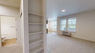 This well-appointed two-bedroom, two-bathroom unit at 1948 Linwood St NW in Salem, Oregon offers a thoughtfully designed single-floor layout. The kitchen is a standout feature, showcasing warm wood-tone cabinetry, white countertops, stainless steel appliances including a refrigerator, electric range, and built-in microwave, all complemented by light hardwood-style flooring and a window overlooking greenery. The open living area is carpeted and anchored by a corner fireplace, creating a cozy focal point, while an adjacent nook houses a side-by-side washer and dryer for added convenience. Both bedrooms are carpeted and filled with natural light from windows with views of the surrounding area. The primary bedroom is generously sized and features a walk-in closet outfitted with wire shelving and hanging rods for ample storage. The bathrooms are clean and functional, with one featuring a full tub/shower combo and the other with a wood-tone vanity, white countertop, and large mirror. Neutral tones, recessed lighting, and consistent finishes create a cohesive, modern ambiance throughout the entire unit.