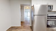 This two-story home offers a practical and clean layout across two levels, combining updated finishes with functional living spaces throughout. The main level features hardwood-style flooring that flows seamlessly from the kitchen through the hallway and into the living area. The kitchen is equipped with stainless steel appliances — including a refrigerator, oven, microwave, and dishwasher — complemented by white shaker-style cabinetry and dark countertops that provide a sharp contrast. The living room is a standout space, highlighted by a white stone fireplace and a sliding glass door fitted with vertical blinds that opens to an outdoor patio, allowing for generous natural light. A carpeted staircase with an ornate white wrought-iron railing connects the main level to the upper floor. The upper level hosts multiple bedrooms, each finished with neutral carpet, vertical blind-covered windows, and ample built-in closet storage. A full bathroom with a tub-shower combination and hardwood-style flooring serves the upper level. Textured ceilings are consistent throughout the home, adding a classic architectural touch. The overall aesthetic is bright, clean, and move-in ready.