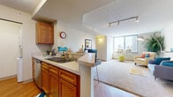 Located at 1254 Hennepin Ave in the heart of Minneapolis, this one-bedroom, one-bathroom unit offers a well-designed layout across a single floor. The open-concept kitchen is equipped with warm wood cabinetry, stainless steel appliances including a refrigerator, microwave, and range, and a peninsula breakfast bar with seating — ideal for casual dining. Wood-look flooring runs through the kitchen and entry area, creating a clean, cohesive aesthetic. Track lighting in the living area adds a modern touch, while a large picture window frames sweeping views of the Minneapolis skyline, flooding the space with natural light. The generously sized bedroom is a standout feature, boasting a curved wall of floor-to-ceiling windows that deliver breathtaking panoramic city views — a truly remarkable focal point. Soft carpeting and ample closet space complete the bedroom. The bathroom features a full tub-shower combination with tile surround and hardwood-style flooring. An in-unit laundry area adds everyday convenience. The overall ambiance is bright, urban, and functional — well-suited for those looking to experience vibrant city living in one of Minneapolis's most connected corridors.