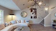 This two-story residence in Horn Lake, Mississippi offers a well-designed layout across two floors, combining modern aesthetics with functional living spaces. The main level features a striking living area anchored by soaring vaulted ceilings and a bold sputnik-style chandelier with brass and glass globe accents. Wood-look flooring flows throughout the main level, complementing the neutral gray walls. A carpeted staircase connects the floors, with wall décor accenting the vertical height of the stairwell.

The kitchen is a galley-style space featuring white cabinetry with contemporary hardware, marble-look quartz countertops, stainless steel appliances, and wood-look flooring. It opens directly into a dedicated dining area, creating a practical and connected layout.

The upper level houses both bedrooms, each finished with plush carpet and stylish pendant lighting. The primary bedroom includes an en-suite bathroom with marble-look countertops and a full mirror. The second bedroom offers ample space with a dedicated desk area and natural light from a window. A half bathroom on the main level and a full bathroom upstairs complete the 2.5-bath configuration, both finished with quartz-look vanity surfaces and clean, neutral tones throughout.