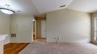 Located at 7820 W Capitol Ave in Little Rock, Arkansas, this single-story home offers a well-organized layout with a variety of functional and comfortable living spaces. The living room is a standout feature, showcasing soaring vaulted ceilings that lend an open, airy feel to the space. A tile-surround fireplace with a clean white mantel serves as the room's focal point, complemented by soft carpeting underfoot. The living area flows seamlessly into the kitchen, which is designed in a galley style with white cabinetry, dark countertops, and black appliances including a refrigerator, range, and dishwasher. Hardwood flooring runs through the kitchen and adds warmth to the space. The bedrooms are generously sized, each featuring plush carpeting, ceiling fans with light fixtures, and windows with blinds that allow for natural light. The primary bedroom includes access to a walk-in closet, providing ample storage. The bathroom is equipped with a tiled tub-shower combination, a hardwood floor, dark countertops, and a large wall mirror. Throughout the home, neutral wall tones create a cohesive and inviting atmosphere, making each room versatile and move-in ready.