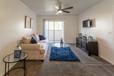 Located at 23402 Hemlock Ave in Moreno Valley, California, this single-floor residence offers a well-organized and functional layout with a warm, neutral aesthetic throughout. The living room serves as the heart of the home, featuring plush carpeting, crown molding, and a ceiling fan that enhances airflow and comfort. A sliding glass door opens to a private balcony, filling the space with natural light and offering pleasant outdoor views of the surrounding greenery and palm trees. The kitchen is clean and efficiently designed, showcasing white cabinetry with ample storage, light-toned countertops, wood-look flooring, and a full suite of white appliances including a range and refrigerator. An L-shaped counter layout maximizes workspace and functionality. The bedrooms are comfortably sized, each carpeted and offering closet space, with windows that allow in natural light. The primary bedroom features a window framing outdoor views, contributing to a relaxed and airy atmosphere. The bathroom is neatly appointed with a white vanity, large mirror, and hardwood-style flooring, maintaining the home's clean and consistent design language. Overall, the residence presents a tidy, move-in-ready space with cohesive finishes and practical amenities throughout.