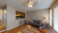 Located at 12630 Ashford Point Dr in Houston, TX, this single-floor residence offers a well-organized layout designed for comfortable everyday living. The living room serves as the heart of the home, featuring warm hardwood-style flooring, a ceiling fan, and a set of French doors that allow natural light to fill the space. A distinctive exposed brick accent wall adds character and texture to the room's neutral color palette.

The kitchen is accessible via a pass-through window with a dark granite-style countertop bar, complemented by two metal bar stools — an efficient and social design that connects the kitchen to the living area. Inside the kitchen, oak wood cabinetry, a black tile backsplash, dark countertops, and a black electric range come together to create a functional cooking space.

The bedrooms are carpeted and each equipped with ceiling fans. The primary bedroom offers a roomy closet and warm, neutral tones, while the secondary bedroom provides a bright window and ample open floor space. Both rooms maintain a calm, restful ambiance.

The bathroom features a dark granite-topped vanity with wood cabinetry, a large mirror with overhead lighting, and a shower-tub combination. Throughout the home, consistent neutral tones and practical finishes create a cohesive and inviting atmosphere.