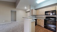 This single-floor residence features 2 bedrooms and 3 bathrooms within a well-organized layout that includes a kitchen, living room, hallway, and dedicated closet space. The living room is a standout area, boasting vaulted ceilings that enhance the sense of openness, a tile-surround fireplace as a central focal point, and a large window that allows natural light to fill the carpeted space. A ceiling fan adds to the room's comfort and functionality.

The kitchen is designed for practicality, featuring light wood cabinetry, granite-style countertops, a peninsula with a built-in sink, and black appliances including a range, refrigerator, and microwave. Wood-look flooring runs through the kitchen, which opens directly into the living area for a connected feel.

The bedrooms are carpeted and well-lit, with windows offering outdoor views and ceiling fans for climate control. The primary bedroom benefits from a spacious walk-in closet outfitted with wire shelving and carpet flooring, providing generous storage capacity.

The bathrooms are clean and classic in design, with one featuring a full tub-shower combo with white tile surround accented by a dark tile border. The hallway connects the rooms efficiently, contributing to the home's straightforward and accessible floor plan.