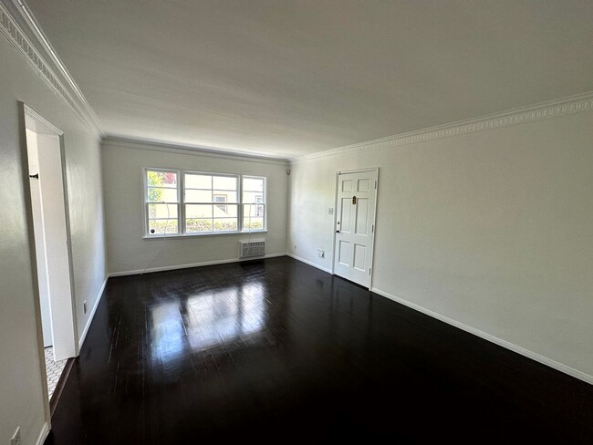 Spacious living room with hardwood floors and large south-facing window. - 624 N Spaulding Ave