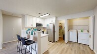 Located at 6801 Bordeaux Ct in Reynoldsburg, Ohio, this single-story home offers a well-organized layout across 12 distinct spaces, delivering a comfortable and functional living environment. The interior is finished with a neutral color palette of soft grays and whites throughout, creating a clean, cohesive aesthetic.

The kitchen is a standout feature, showcasing white cabinetry with black hardware, stainless steel appliances including a refrigerator, range, and microwave, and a peninsula with bar seating. Light wood-look flooring carries through the kitchen and into adjacent areas. A convenient pantry or storage closet is accessible directly from the kitchen, alongside an in-unit laundry area housing a full-size top-loading washer and dryer with overhead wire shelving.

The living area features light wood-look flooring and a glass-door fireplace framed in white, offering a cozy focal point. Bedrooms are carpeted in warm neutral tones and receive natural light through windows fitted with blinds. The bathrooms are tastefully updated with white vanities, black hardware accents, and light wood-look tile flooring — one includes a tub-shower combination. A welcoming entryway with light hardwood flooring leads into the main living spaces. The attached garage provides added convenience and storage capacity with a textured ceiling and automatic opener.