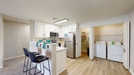 Located at 6801 Bordeaux Ct in Reynoldsburg, Ohio, this single-story home offers a well-organized layout across 12 distinct spaces, delivering a comfortable and functional living environment. The interior is finished with a neutral color palette of soft grays and whites throughout, creating a clean, cohesive aesthetic.

The kitchen is a standout feature, showcasing white cabinetry with black hardware, stainless steel appliances including a refrigerator, range, and microwave, and a peninsula with bar seating. Light wood-look flooring carries through the kitchen and into adjacent areas. A convenient pantry or storage closet is accessible directly from the kitchen, alongside an in-unit laundry area housing a full-size top-loading washer and dryer with overhead wire shelving.

The living area features light wood-look flooring and a glass-door fireplace framed in white, offering a cozy focal point. Bedrooms are carpeted in warm neutral tones and receive natural light through windows fitted with blinds. The bathrooms are tastefully updated with white vanities, black hardware accents, and light wood-look tile flooring — one includes a tub-shower combination. A welcoming entryway with light hardwood flooring leads into the main living spaces. The attached garage provides added convenience and storage capacity with a textured ceiling and automatic opener.