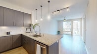 This 1-bedroom, 1-bathroom residence in San Diego's 92101 zip code offers a well-designed layout with modern finishes throughout. The open-concept living and kitchen area serves as the heart of the unit, featuring light hardwood-style flooring, a ceiling fan, track lighting, and sliding glass doors that lead to a private balcony with outdoor views, filling the space with natural light.

The kitchen is a standout feature, showcasing dark espresso cabinetry with sleek hardware, granite countertops, a peninsula with an undermount sink and a professional-style pull-down faucet, pendant lighting, white subway tile backsplash, and stainless steel appliances including a full-size refrigerator and gas range. Ample upper and lower cabinetry provides generous storage.

The bedroom offers a quieter retreat, finished with plush carpeting, a large window allowing natural light, and neutral tones throughout. A dedicated closet provides organized storage space.

The bathroom is clean and contemporary, featuring tile flooring, a dark wood vanity with a white countertop, and a full tub-shower combination with white subway tile surround. A hallway connects the rooms, completing this efficient and thoughtfully designed San Diego residence.