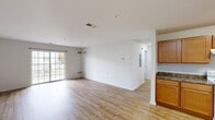Located at 23033 Meadow Wood Ct in Seaford, Delaware, this single-floor home offers a clean, functional layout designed for comfortable everyday living. The open living and dining area is finished with light-toned hardwood-style flooring that extends throughout the main living spaces, creating a bright and cohesive feel. A sliding glass door fills the living room with natural light and provides a view of the outdoors, enhancing the sense of openness throughout the space. The kitchen is well-appointed with warm honey-toned cabinetry, dark granite-style countertops, and white appliances including a range, dishwasher, and refrigerator. Ample cabinet storage and counter space make this an efficient and practical cooking area. The bedrooms feature neutral carpet flooring and crisp white walls, providing a calm and versatile environment. One bedroom benefits from a large window with blinds, inviting in generous natural light. The bathrooms each include a full tub-and-shower combination with clean white surrounds and chrome fixtures. Throughout the home, a consistent neutral color palette and clean finishes create a move-in-ready atmosphere well-suited for a variety of living arrangements.