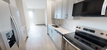 This 470-square-foot studio apartment at unit 1201 308 offers a well-designed single-floor layout that maximizes functionality within a compact footprint. The space features light-toned hardwood flooring throughout, contributing to a bright and cohesive aesthetic.

The galley-style kitchen is a standout feature, equipped with stainless steel appliances including a refrigerator, electric range, built-in microwave, and dishwasher. Gray shaker-style cabinetry lines both upper and lower sections, complemented by white countertops and a single-basin undermount sink. Recessed ceiling lights illuminate the kitchen corridor efficiently.

The open living area benefits from natural light streaming through a sliding glass door that leads to a balcony, creating an airy feel despite the studio's size. Clean white walls and a neutral color palette enhance the sense of space.

The bathroom is thoughtfully appointed with a wide vanity featuring gray cabinetry, a white countertop with an undermount sink, and a large mirror. The room maintains the same light wood flooring and clean white walls found throughout the unit. A dedicated closet provides additional storage. The overall design is modern and clean, making efficient use of every square foot.