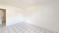 Located at SW 65th Ave in Miami, FL 33143, this one-bedroom, one-bathroom unit offers a compact and efficiently designed single-floor layout. Light-colored ceramic tile flooring runs throughout the entire space, lending a clean, cohesive look to each room.

The combined kitchen and living area greets you at the entrance, where large grid-pane windows allow generous natural light to fill the space and provide views of the surrounding outdoor area. The kitchen features white cabinetry, a stainless steel sink, granite-style countertops, and a pass-through window that connects to the living area — a practical and open design detail that enhances the sense of space.

The bedroom is a well-sized private retreat, fitted with tile flooring consistent with the rest of the unit, a window with natural light, and direct access to the adjacent hallway. Its layout accommodates standard furnishings comfortably.

The bathroom includes a full tub-shower combination adorned with classic white mosaic tile accented by colorful square tile details, adding a retro charm. A granite-style vanity countertop with an integrated sink completes the bathroom's functional design.

Overall, the unit presents a bright, clean, and straightforward aesthetic, with white walls and abundant natural light creating an airy atmosphere throughout.