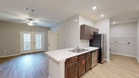 This single-story unit in Central, SC offers a thoughtfully designed layout that maximizes functionality within a compact footprint. The open-concept kitchen serves as a central feature, equipped with stainless steel appliances including a gas range, microwave, refrigerator, and dishwasher. Rich dark-toned cabinetry is paired with light marble-pattern countertops, and a peninsula with an undermount sink provides additional workspace. Light wood-tone flooring runs throughout the main living areas, creating a cohesive, clean aesthetic complemented by recessed lighting and neutral gray walls.

The living area is accessible directly from the kitchen and receives natural light through a glass-paneled entry door. A ceiling fan is installed overhead. The bedroom is a comfortable size, carpeted for warmth, and features two windows that allow ample natural light and outdoor views. A ceiling fan and dedicated closet—equipped with wire shelving systems on multiple walls—add practicality to the space.

The bathroom includes a single-vanity with dark wood cabinetry, a framed mirror, and a tub-shower combination with a curved curtain rod and grab bar. Light wood-tone flooring continues throughout the bathroom, maintaining a consistent finish across the unit.