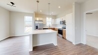 This thoughtfully designed 2-bedroom, 3-bathroom single-floor residence offers a clean, modern aesthetic throughout. The open-concept kitchen and living area serves as the heart of the home, featuring warm wood-tone lower cabinetry paired with crisp white upper cabinets, a classic subway tile backsplash, stainless steel appliances including a French door refrigerator, electric range, and over-the-range microwave, all set atop durable wood-look plank flooring. A built-in cabinet unit provides additional storage at the living room entry.

The bedrooms are finished with plush carpet and neutral walls, offering a comfortable retreat. The primary bedroom is generously sized with a ceiling fan, dual windows with exterior views, and access to a private en-suite bathroom. The en-suite features wood-tone cabinetry, a white countertop vanity, and a walk-in closet with built-in shelving and hanging rods. A second walk-in closet with multi-level shelving provides exceptional storage capacity.

Two dedicated laundry areas are a standout feature, one equipped with a full-size Whirlpool washer and dryer set with overhead shelving. Consistent wood-look plank flooring runs through the main areas, while carpet adds warmth to the bedrooms, creating a cohesive and inviting atmosphere throughout.