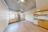 Located at 1400 Madison St in Seattle's First Hill neighborhood, this one-bedroom, one-bathroom unit offers a thoughtfully designed layout across a single floor. The living area is a standout space, characterized by dramatic exposed concrete ceilings with an industrial aesthetic, light hardwood-style flooring, and large windows that frame city views and fill the room with natural light. A ceiling fan adds functional comfort to this open, airy area.

The galley-style kitchen runs along one wall and is well-appointed with light maple cabinetry extending to the ceiling, white appliances including a refrigerator, electric range with oven, and dishwasher, along with a sink and ample counter space. A window at the end of the kitchen brings in additional natural light.

The bedroom is a quiet, carpeted retreat with its own natural light source and access to two closets, providing generous storage. The bathroom features a wide vanity with a single sink, light maple cabinetry, and a large mirror, with grab bars reflecting an accessible design. The unit's warm, neutral color palette, consistent wood-toned door frames, and clean finishes throughout create a cohesive and modern living environment.
