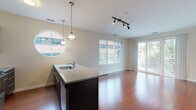 Located at 163 Franklin St in Stamford, Connecticut, this modern single-floor residence offers a well-appointed, open-concept layout designed for comfortable urban living. The kitchen is a standout feature, showcasing dark espresso cabinetry, stainless steel appliances including a full-size refrigerator, built-in microwave, and range, as well as a granite-topped island with a built-in sink and elegant pendant lighting. A distinctive circular window adds architectural character to the kitchen area, flooding it with natural light. Rich hardwood flooring flows throughout the main living areas, complementing the clean, neutral color palette. The living area is generously proportioned, with large windows and sliding glass doors that open to a private balcony, bringing in abundant natural light and outdoor views. The bedrooms are carpeted for comfort and feature wide windows with blinds, providing a calm and restful atmosphere. Two full bathrooms are finished with dark-tiled flooring, white tiled tub-shower combinations, sleek dark vanities with white countertops, and chrome fixtures, reflecting a consistent modern aesthetic throughout. The overall ambiance of the space is clean, contemporary, and bright, offering a refined residential experience in the heart of Stamford.