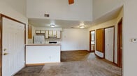Located at 19 Willow Creek Dr in Battle Creek, Michigan, this one-bedroom, two-bathroom home offers a practical and comfortable single-floor layout. The open-concept living and kitchen area is anchored by soaring vaulted ceilings and a ceiling fan, creating an airy, spacious feel. The kitchen features wood-toned cabinetry, white appliances including a gas range, dishwasher, and refrigerator, along with a double sink and durable wood-look flooring. A peninsula counter separates the kitchen from the carpeted living area, which flows naturally through the space. The bedroom is generously sized, with soft carpet, a ceiling fan, and sliding glass doors that open to a private balcony with neighborhood views. A closet with built-in shelving is conveniently located adjacent to the bedroom, alongside an in-unit stacked washer and dryer. The two bathrooms include a full bath with a tub/shower combo and wood-look flooring, and a second bathroom accessible from the bedroom hallway. Neutral tones and warm wood trim throughout give the home a clean, cohesive aesthetic well-suited for everyday living.