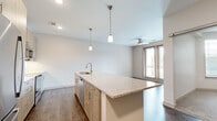 Located at 350 Old Hickory Blvd in Nashville, TN, this one-bedroom, one-bathroom residence offers a thoughtfully designed open-concept layout with contemporary finishes throughout. The kitchen serves as the centerpiece of the living space, featuring light wood cabinetry, stainless steel appliances, a subway tile backsplash, and a generous granite-topped island with an integrated sink and gold-accented hardware. Dual pendant lights illuminate the island, while recessed lighting brightens the full kitchen area. Dark hardwood-style flooring extends through the main living and kitchen areas, creating a warm, modern aesthetic. The living area flows naturally toward a glass door that opens to a balcony, allowing for natural light and outdoor views. The bedroom is carpeted for comfort, with a ceiling fan, and large windows fitted with blinds that bring in ample natural light. A dedicated walk-in closet with wire shelving provides generous storage and connects directly to the full bathroom. The bathroom is well-appointed with a granite-topped vanity with wood cabinetry, a tub-shower combination, and wood-look tile flooring. Clean lines, neutral tones, and modern fixtures give the entire residence a cohesive and polished feel.