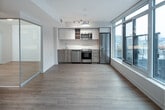 Located at 39 Niagara St in Toronto's vibrant King West neighbourhood, this single-floor unit combines modern design with functional living spaces. Light hardwood flooring runs throughout, complementing the clean, neutral palette of white walls and contemporary finishes.

Large floor-to-ceiling windows are a defining architectural feature, flooding the living and bedroom areas with natural light while offering views of the surrounding urban streetscape. The open-concept living area flows seamlessly toward the kitchen, which is outfitted with stainless steel appliances, including a full-size refrigerator, electric range, built-in microwave, and dishwasher. Cabinetry features a mix of white uppers and wood-toned lower drawers, with a subway tile backsplash adding a clean, modern touch.

The bedroom is generously proportioned with large windows framing city views, and light hardwood flooring continues throughout. The bathroom is finished in a crisp, all-white scheme with subway tile surrounding a soaker tub and shower combination, complemented by a wood-toned vanity with a white countertop. The entry hallway provides a smooth transition into the main living spaces, maintaining the unit's bright and cohesive aesthetic.