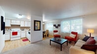 Located at 2175 Cubit St in Eugene, Oregon, this single-floor residence offers a well-designed layout that balances comfort and functionality. The open-concept living and dining area serves as the heart of the home, featuring plush carpet flooring, a textured ceiling, and large windows dressed with sheer curtains that allow abundant natural light and views of surrounding greenery. The living room provides generous space for seating and relaxation, with a warm, inviting ambiance.

The kitchen is efficiently arranged in an L-shaped configuration, showcasing white cabinetry with light wood trim, white appliances including an electric range and dishwasher, light-toned laminate flooring, and ample counter space. A half-wall with a decorative mirror separates the kitchen from the main living area, maintaining an open feel while defining each zone.

The bedrooms are carpeted and well-proportioned, each featuring windows with blinds and curtains that offer privacy and natural light. One bedroom includes a sliding-door closet, providing practical storage. The bathroom features light wood-style flooring, a vanity with storage cabinetry, and a clean, functional layout. Throughout the residence, a cohesive neutral color palette is accented by warm earth tones, creating a comfortable and welcoming atmosphere.