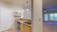 Located at 6601 S West Shore Blvd in Tampa, FL, this single-floor residence offers a well-organized layout with a cohesive, neutral design throughout. The open living area is generously sized, featuring plush wall-to-wall carpeting, crown molding, and a ceiling fan with light fixture. It flows directly into the kitchen, which is separated by a raised breakfast bar, creating a connected yet defined space. The galley-style kitchen is equipped with light wood cabinetry, granite countertops with a decorative tile backsplash, stainless steel appliances including a refrigerator with ice maker, a built-in dishwasher, and pendant lighting overhead. Light-toned tile flooring runs throughout the kitchen, adding a clean, practical finish. The bedroom is a comfortable, carpeted room with a ceiling fan and a window fitted with blinds, allowing for natural light and privacy. The full bathroom features a granite double-vanity with wood cabinetry, large-format tile flooring, and a soaking tub with a tiled shower surround. A separate half bathroom includes a pedestal sink, toilet, and tile flooring, providing added convenience. The overall ambiance is calm and functional, with warm neutral tones and consistent finishes throughout the space.