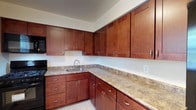 This single-floor residence at Leonardine Gardens, D4B, offers a thoughtfully designed layout with a clean, neutral aesthetic throughout. The kitchen is a functional highlight, featuring rich warm-toned cabinetry with shaker-style doors and brushed nickel hardware, complemented by granite countertops in earthy tones. Black appliances, including a gas range, microwave, and sink, are integrated seamlessly, while light tile flooring ties the space together.

The living and dining areas are finished with gleaming hardwood floors that extend throughout the unit, lending warmth and continuity. A sliding glass door in the dining area floods the space with natural light and provides access to an outdoor area, enhanced by an elegant pendant light fixture overhead. A wall-mounted air conditioning unit and baseboard heating ensure year-round comfort.

The bedrooms are well-proportioned, each featuring hardwood flooring, natural light from windows, and ample closet space, including a dedicated walk-in-style closet in one room. The bathroom is finished in clean white tiling, with a full bathtub and shower combination, a window allowing natural light, and classic chrome fixtures. Overall, the unit presents a bright, functional, and comfortable living environment.