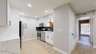 This thoughtfully designed 2-bedroom, 1-bathroom unit offers a clean, contemporary aesthetic across its efficiently planned single-floor layout. The combined kitchen and living area serves as the heart of the home, featuring a modern kitchen outfitted with white shaker-style cabinetry, a bold black hexagonal tile backsplash, light quartz countertops, and a full suite of stainless steel appliances including a gas range, built-in microwave, dishwasher, and refrigerator. Recessed lighting illuminates the space, while light wood-style vinyl plank flooring runs seamlessly throughout the entire unit, lending warmth and visual continuity.

Both bedrooms are well-proportioned and finished with the same light flooring, neutral gray walls, and white trim. Each room is equipped with a ceiling fan, providing comfort and air circulation. The primary bedroom offers a generous footprint, while the secondary bedroom includes a window with natural light. A dedicated closet provides additional storage.

The bathroom is appointed with a full bathtub and shower combination, featuring floor-to-ceiling marble-look white tile surround and matte black fixtures, creating a clean, modern contrast. The unit's consistent palette of whites, grays, and natural wood tones creates a cohesive and contemporary living environment throughout.
